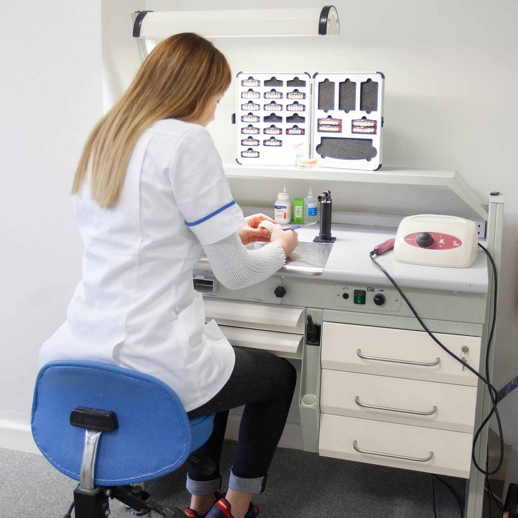 A dentist carefully finishing off dentures in a denture laboratory 